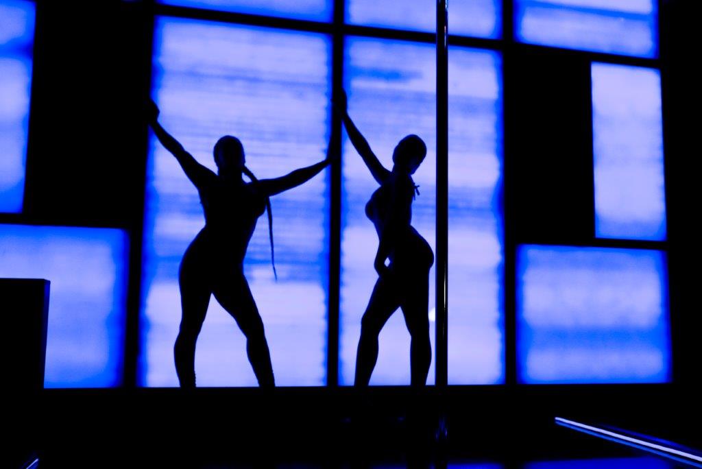 Two dancers silhouette dance in front of neon wall Minneapolis